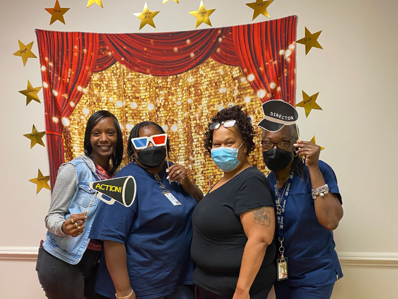 A group of four SOAR365 direct support professionals posing in front of a sparkly backdrop with stars.