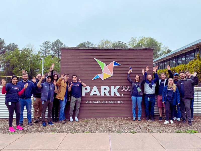 Group of smiling volunteers standing in front of PARK365 sign.