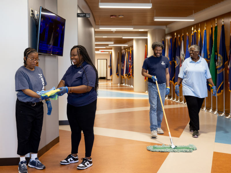 SOAR365 janitorial and custodial employees holding rags and mopping.