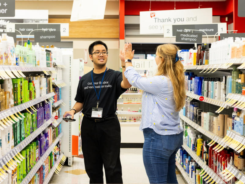A Supported Employment participant high fives his job coach as she supports him in completing his work duties at Walgreens.